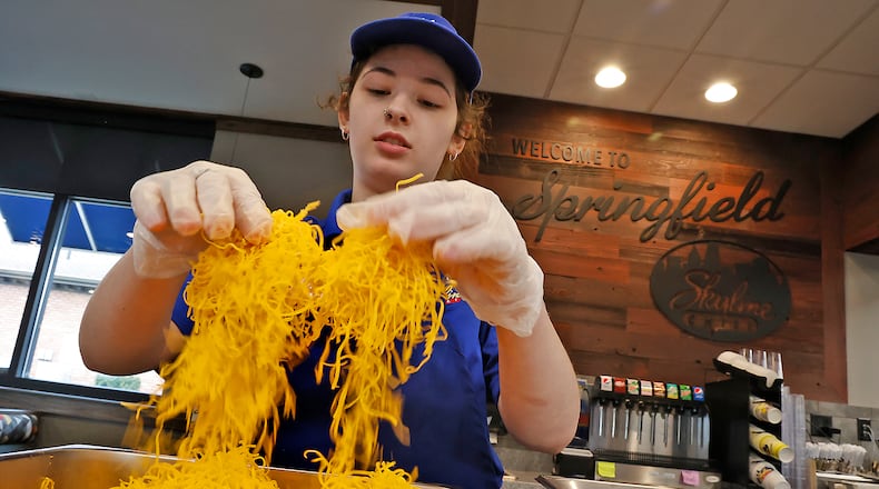 Brooklynn Knox, an employee at the new Skyline Chili in Springfield, fluffs the cheese before dividing it up into individual bags Wednesday, March 22, 2023. The employees and managers have been getting the new restaurant ready for it's grand opening on Thursday. BILL LACKEY/STAFF
