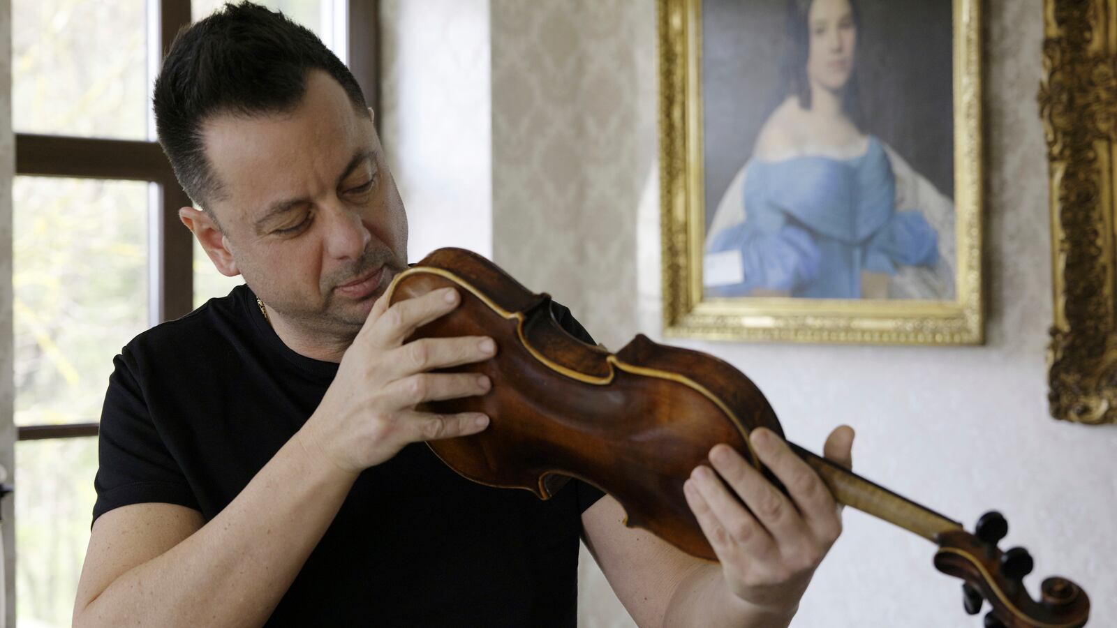 Art collector Tamás Tálosi holds a Dachau-built instrument dubbed the ''violin of hope'', in Magyarpolány, Hungary, Tuesday April 22, 2025. (AP Photo/Nikolett Csanyi)