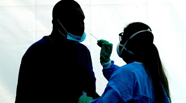 A man is silhouetted against the wall of a white tent, illuminated by the sun, as he gets a COVID-19 test on Dec. 18 at the Clark County Combined Health District's free COVID testing clinic at Hayward Middle School.