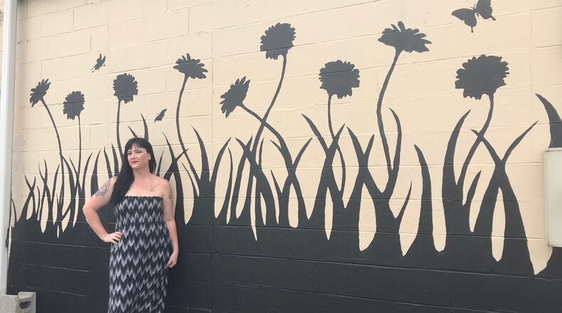 Cherish Harrell Brooks outside her shop, The Secret Chamber House of Oddities and Artwork, in front of a mural she just completed to remember the nine Oregon District shooting victims.