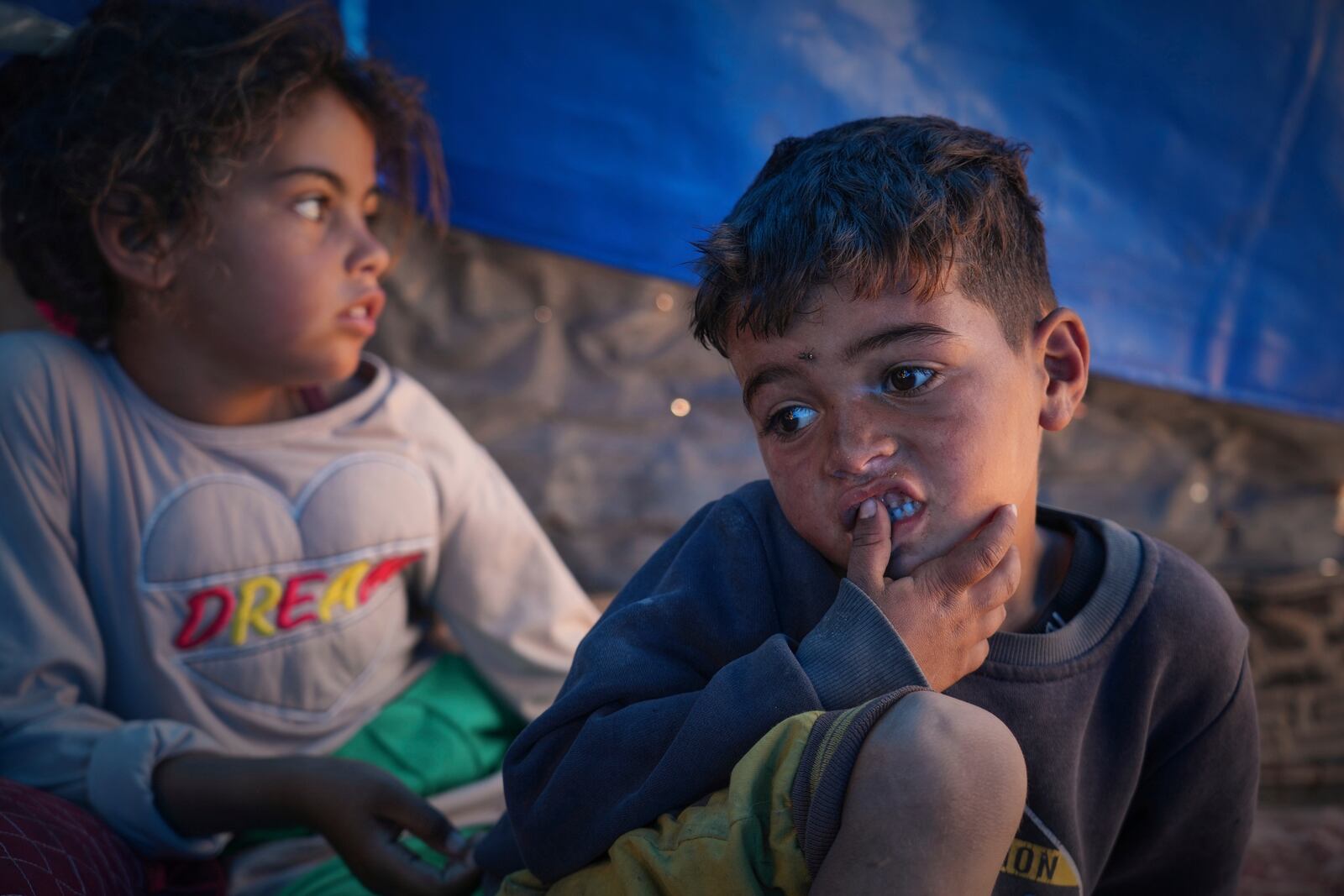 Raed Zaharna, right, and his sister Sally sit in their family tent after their mother, Ward, returned empty-handed from trying to receive donated food at a community kitchen in Khan Younis, in the southern Gaza Strip, Friday, May 9, 2025. (AP Photo/Abdel Kareem Hana)