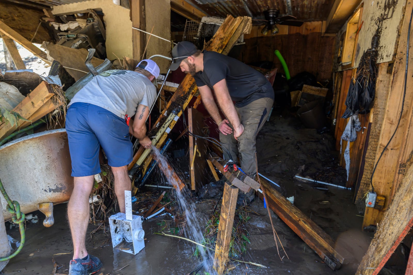 Wes Schenki, left and Neal Clawson work to shut off exposed water pipes in a cabin situated along the Rio Ruidoso Wednesday morning, July 9, 2025, in Ruidoso, N.M., after the town was hit with major flooding the day before. (AP Photo/Roberto E. Rosales)