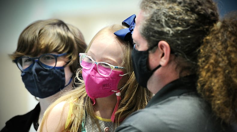 Joy Minor, age 9, waits with brother, Jay, left, and father, Paul, right, for her COVID-19 vaccine at Dayton Children's earlier this month. MARSHALL GORBY\STAFF