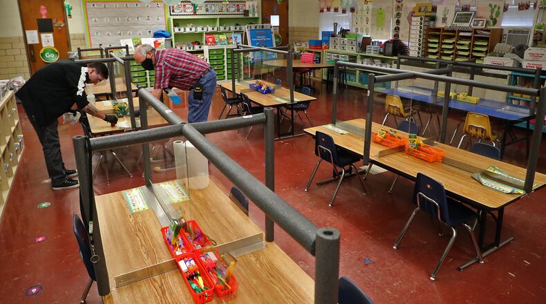 Joseph Blake, left, and Vennis Williams clean and sanitize a kindergarten class room at Enon Primary School. BILL LACKEY/STAFF