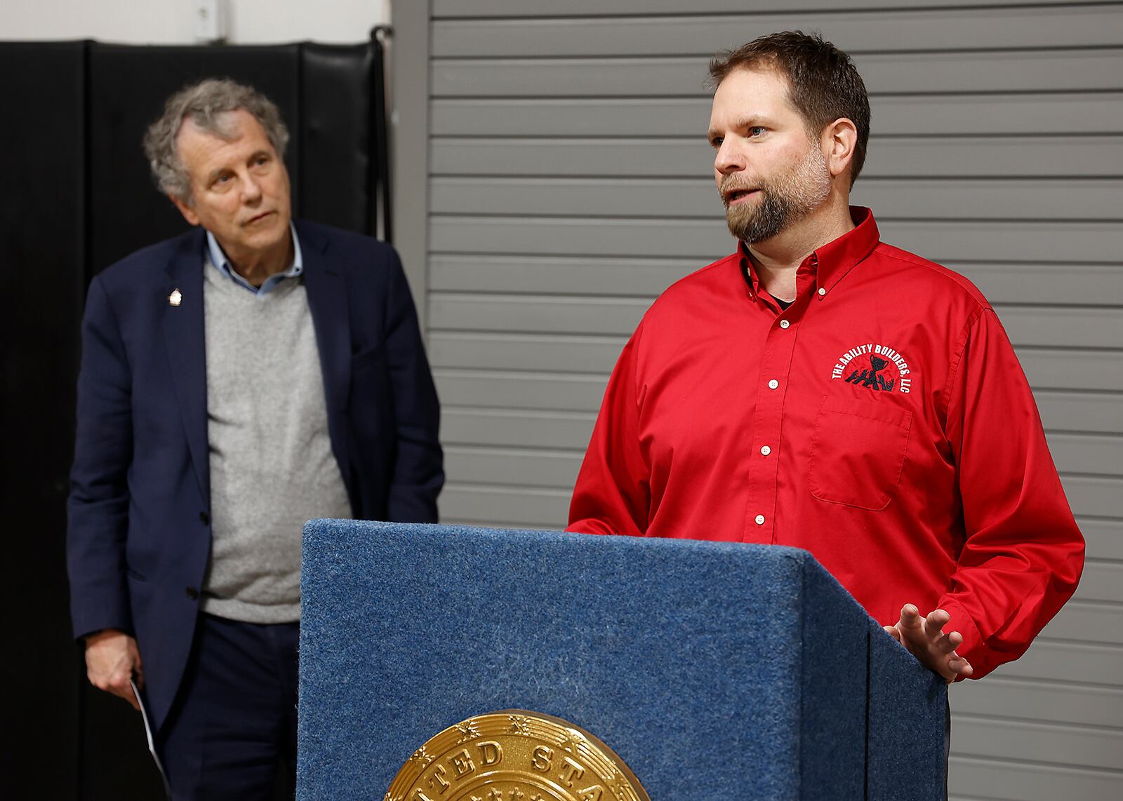 Senator Sherrod Brown listens to Lane Martin, owner of The Ability Builders, talk about how the train derailment just a few yards away affected his business during a press conference Friday, March 24, 2023. BILL LACKEY/STAFF