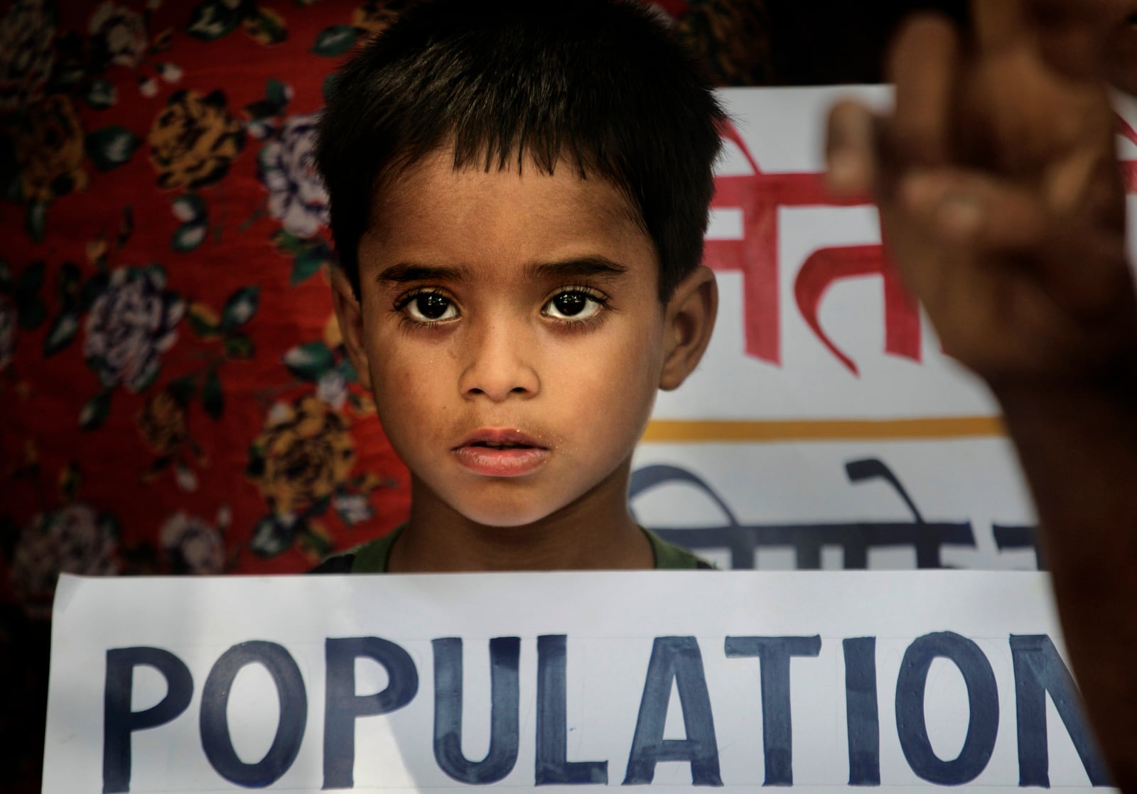 FILE -A boy holds a banner during a demonstration by local activists demanding "Population Control Bill" for two children per couple, on World Population Day in New Delhi, India, July 11, 2011. (AP Photo/Manish Swarup, , File)