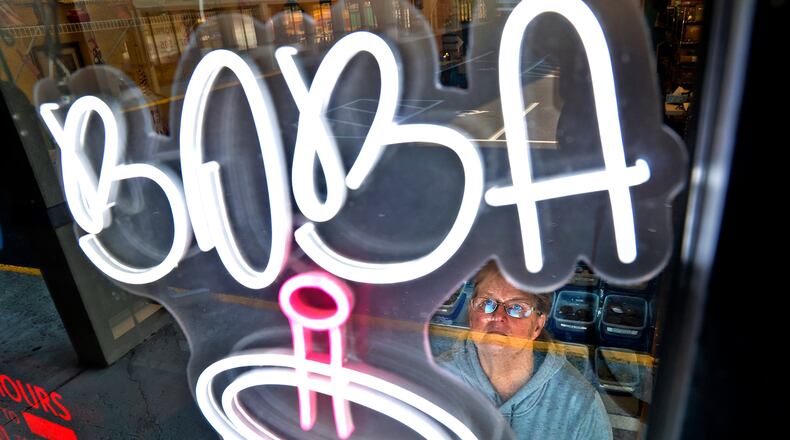 Shari Donnelly, owner of It's Your Party Bakery, looks up a the new neon sign advertising Boba Tea Tuesday, Nov. 22, 2022 in her bakery window. BILL LACKEY/STAFF
