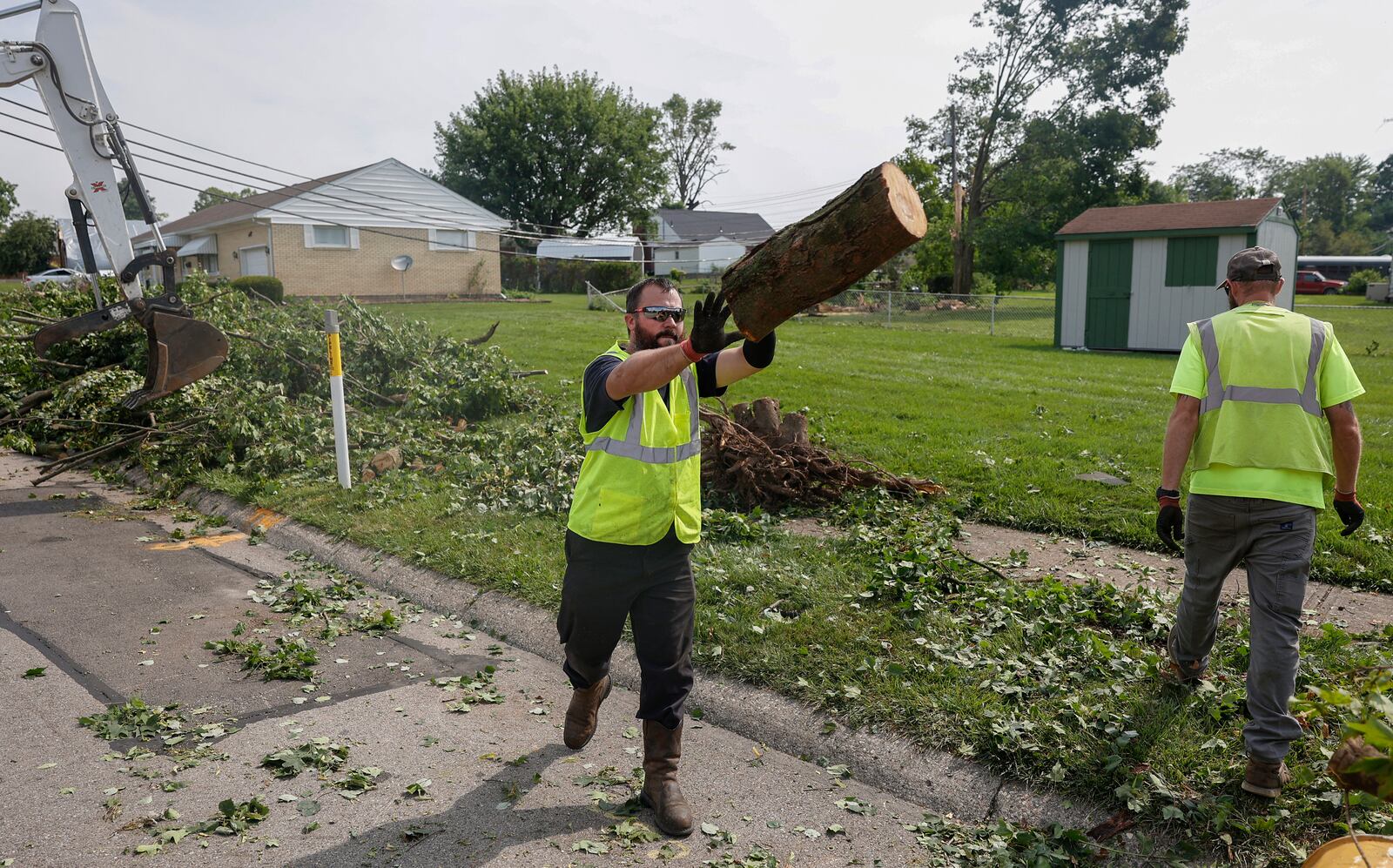 Quienten Sparks, of the Clark County Engineer Road Department, tosses a tree branch in a truck to clean up debris on Monday, July 21, 2025, following a storm that happened over the weekend in Moorefield Township. JOSEPH COOKE/STAFF
