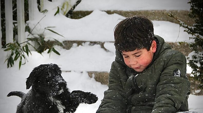 Liam Lewis, 9, plays in the snow with his puppy Shadow, Friday February 4, 2022.