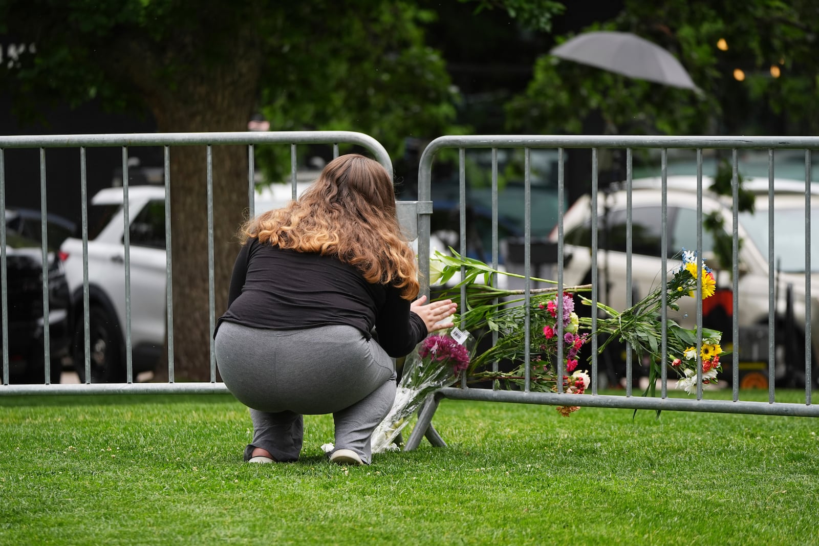 Alexandra Posnock, who moved a month ago from Skokie, Ill., to Boulder, Colo., places a bouquet of flowers along a makeshift barrier outside of the Boulder County, Colo., courthouse after Sunday's attack, Monday, June 2, 2025, in Boulder, Colo. (AP Photo/David Zalubowski)