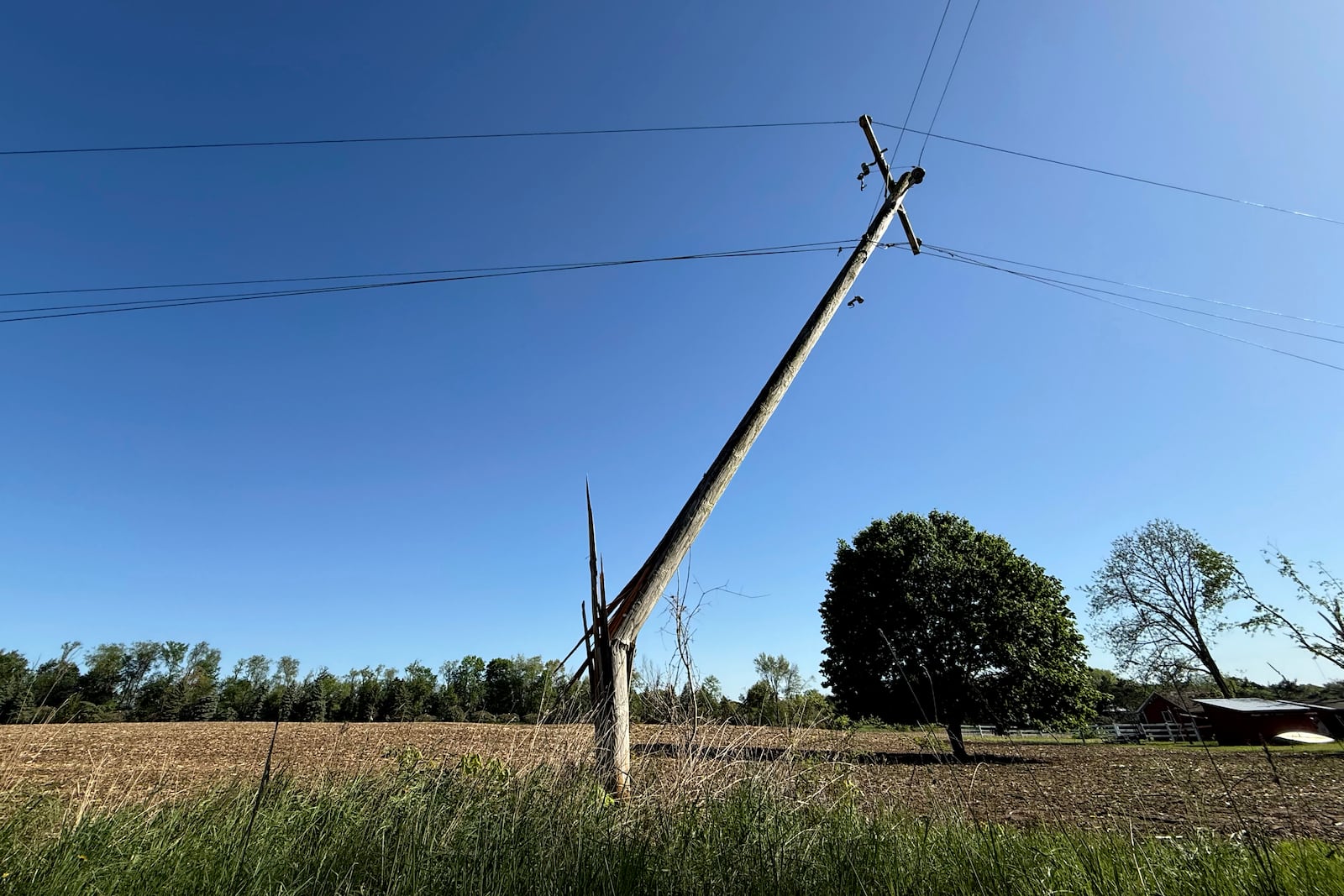 A snapped utility pole stands awkwardly off of 92nd Street near Caledonia, Mich. on Friday, May 16. 2025. (Neil Blake/The Grand Rapids Press via AP)