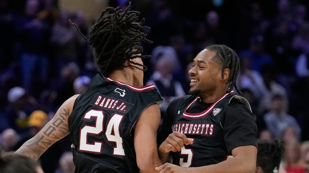 Massachusetts guard Marcus Banks (24) and guard K'jei Parker (5) celebrate after Massachusetts defeated Miami in a basketball game in the quarterfinals of the Mid-American Conference tournament, Thursday, March 12, 2026, in Cleveland. (AP Photo/Sue Ogrocki)