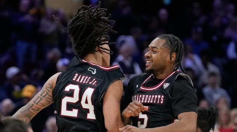 Massachusetts guard Marcus Banks (24) and guard K'jei Parker (5) celebrate after Massachusetts defeated Miami in a basketball game in the quarterfinals of the Mid-American Conference tournament, Thursday, March 12, 2026, in Cleveland. (AP Photo/Sue Ogrocki)
