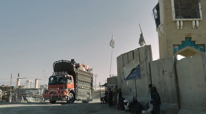 People wait near the closed gate at the Spin Boldak border crossing with Pakistan, after the border was shut for nearly two weeks following clashes between Afghan and Pakistani forces, in Kandahar province, Afghanistan, Thursday, Oct. 23, 2025. (AP Photo/Sibghatullah)