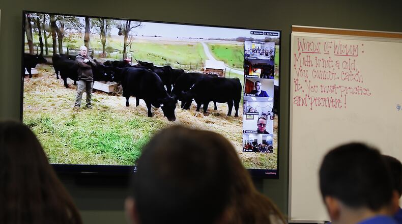Global Impact STEM Academy students go on a virtual field trip Monday as they listen and ask questions of a farmer in his field with his cows from their classroom. Bill Lackey/Staff