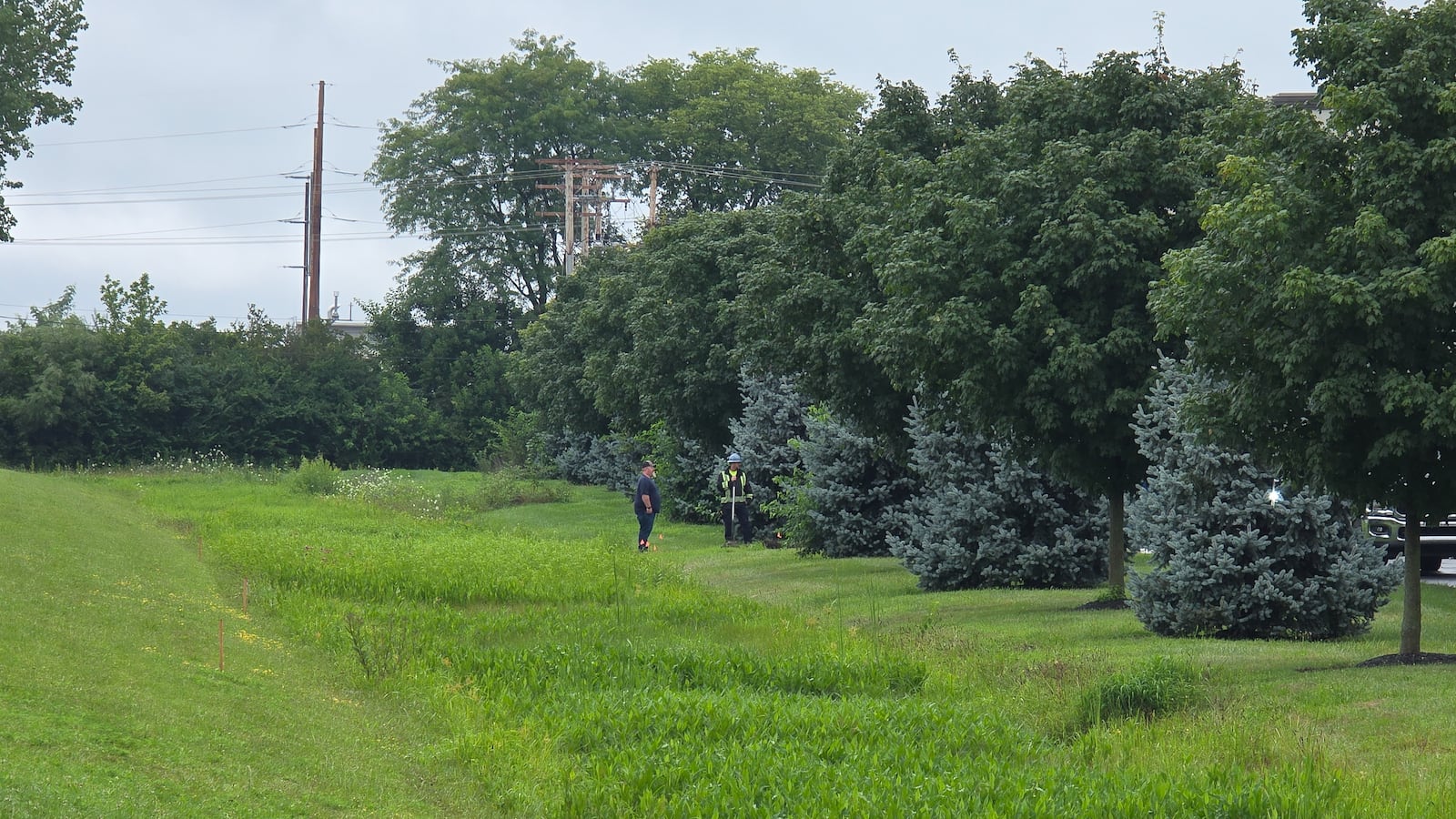 Workers talk near a drainage ditch next to Parker Trutec in PrimeOhio Corporate Park near state Route 41 in Springfield on Thursday, July 31. A water-chemical mix of 1,400 gallons leaked into a drainage ditch that flows into a retention pond on Wednesday night. BRYANT BILLING / STAFF