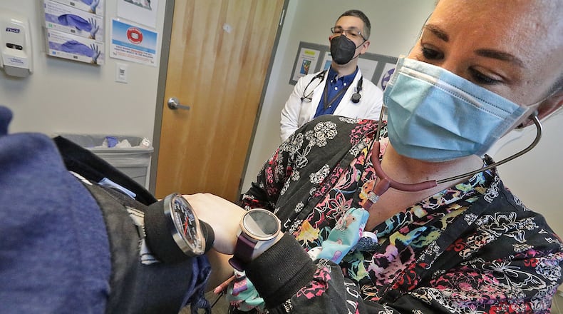 Nurse Heather Nickel takes a patient's blood pressure as Dr. Andres Barrero Ortiz talks to her Wednesday, April 27, 2022 at the Rocking Horse Center in Springfield. BILL LACKEY/STAFF