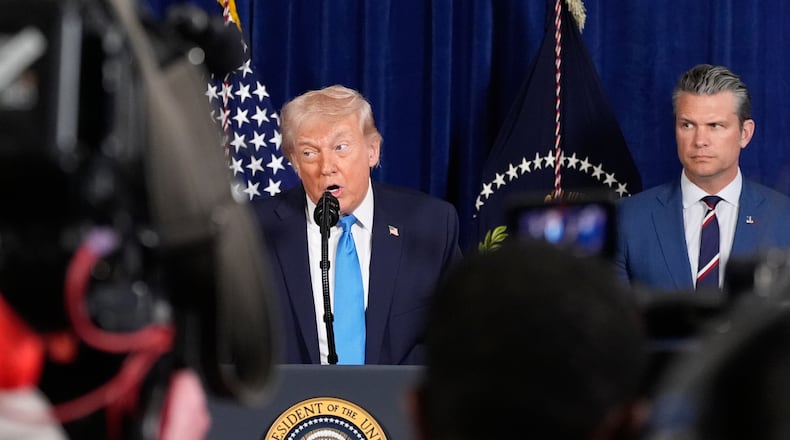 President Donald Trump speaks at his Mar-a-Lago club, Saturday, Jan. 3, 2026, in Palm Beach, Fla., as Defense Secretary Pete Hegseth listens. (AP Photo/Alex Brandon)
