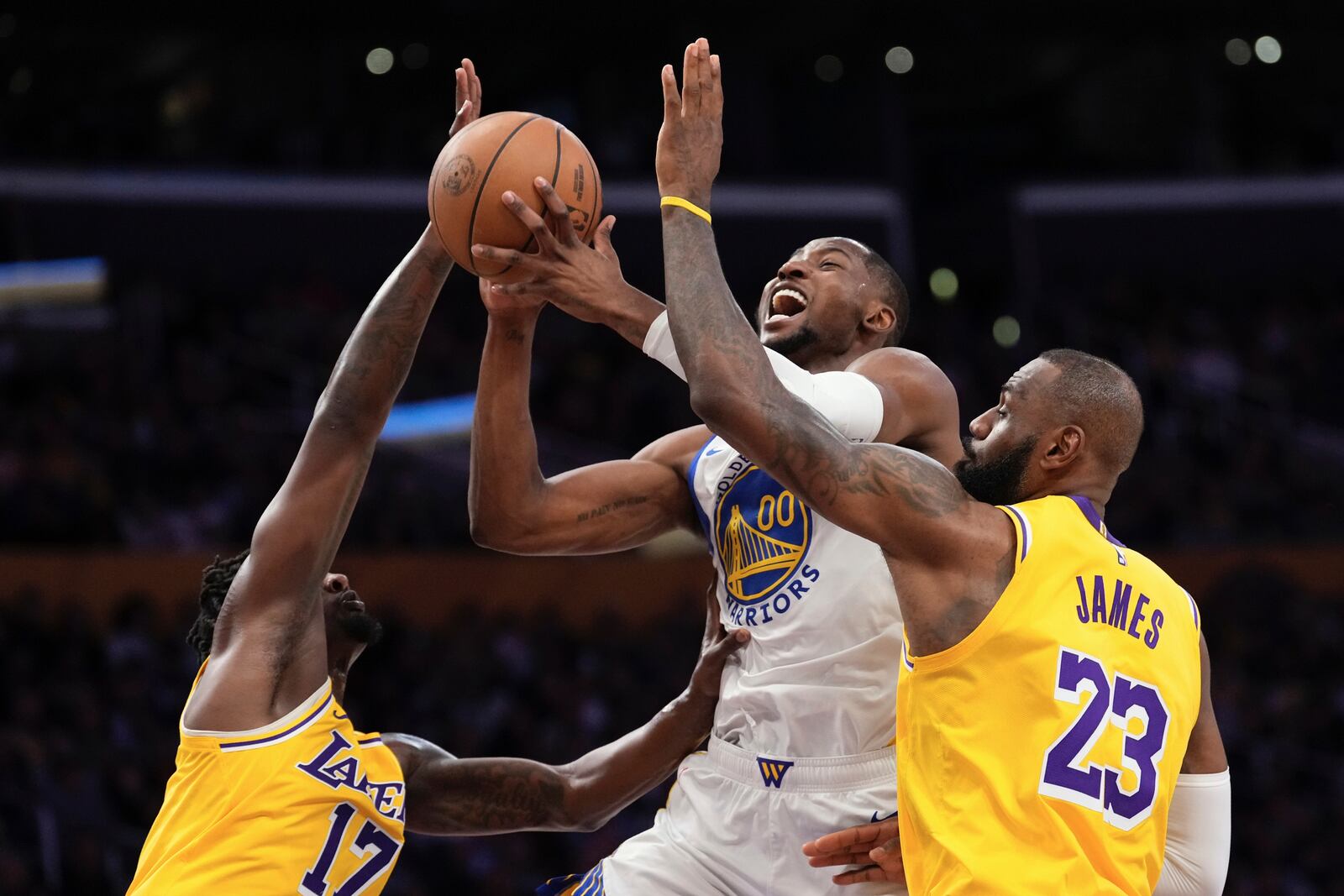 Golden State Warriors forward Jonathan Kuminga, center, shoots as Los Angeles Lakers forward Dorian Finney-Smith, left, and forward LeBron James defend during the first half of an NBA basketball game Thursday, April 3, 2025, in Los Angeles. (AP Photo/Mark J. Terrill)