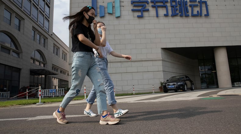 FILE - Women wearing masks to pass by the headquarters of ByteDance, owners of TikTok, in Beijing, China, Aug. 7, 2020. (AP Photo/Ng Han Guan, File)