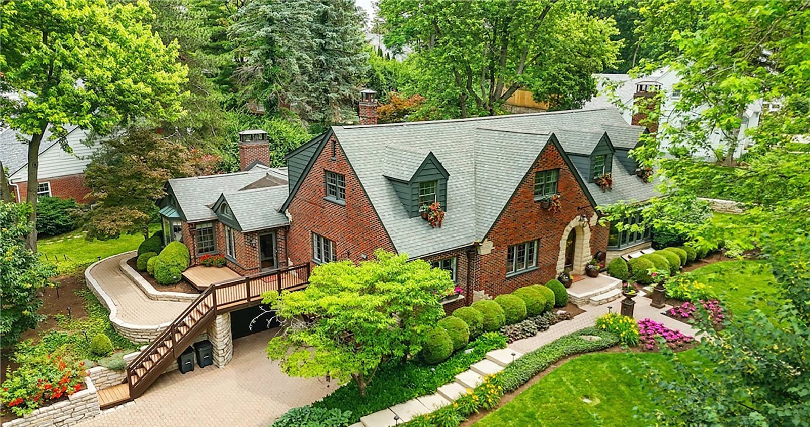 The home features a two car and one car garage (separate) on the basement level of the home, paver walkways and outdoor staircases and paver pathways.
