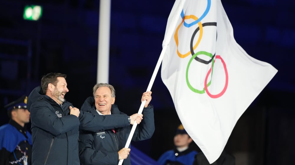 President of the Provence-Alpes-Cote d'Azur Region Renaud Muselier, right, and President of the Auvergne-Rhone-Alpes Region Fabrice Pannekoucke wave the Olympic flag during the closing ceremony of the 2026 Winter Olympics, in Verona, Italy, Sunday, Feb. 22, 2026. (AP Photo/Natacha Pisarenko)