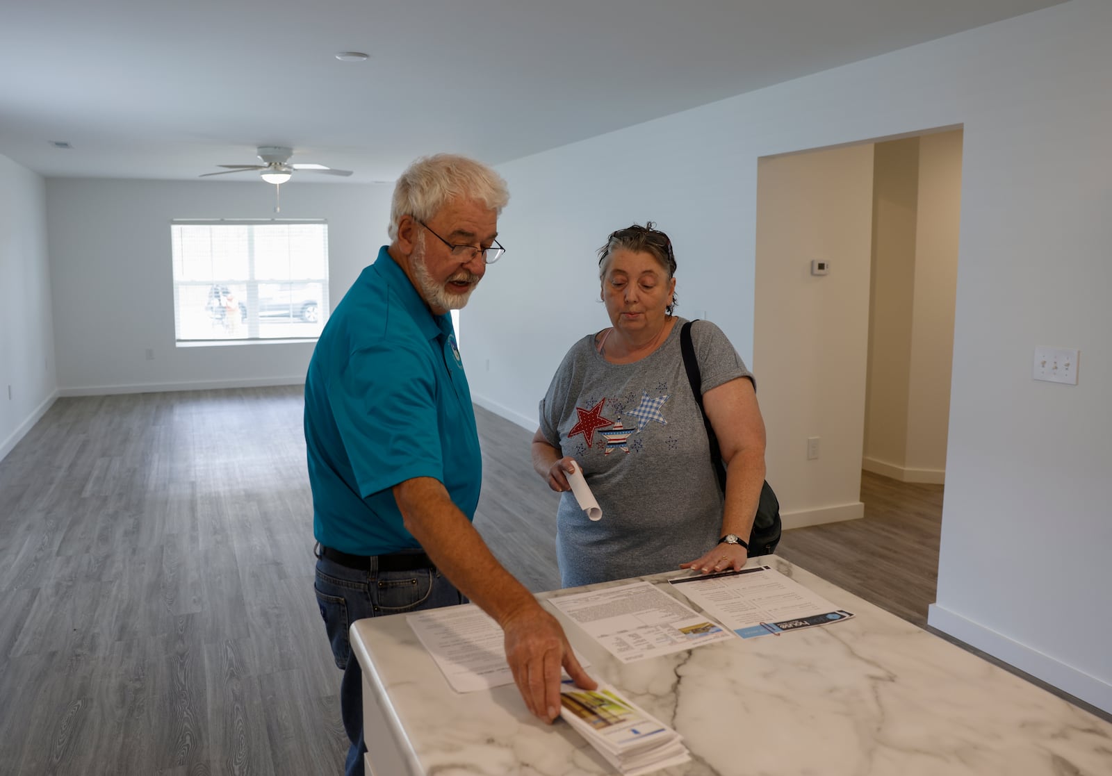 Larry Ricketts, left, candidate of Springfield City Commission, shows Lisa Tilton information about a home during a celebration of the construction of seven homes on Clifton Avenue on Monday, June 9, 2025, in Springfield. JOSEPH COOKE/STAFF