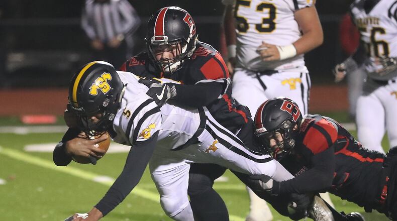 Shawnee’s Robie Glass dives for extra yards as he’s tackled by Bellefontaine’s Ryan Pool and DJ McDonald. BILL LACKEY/STAFF
