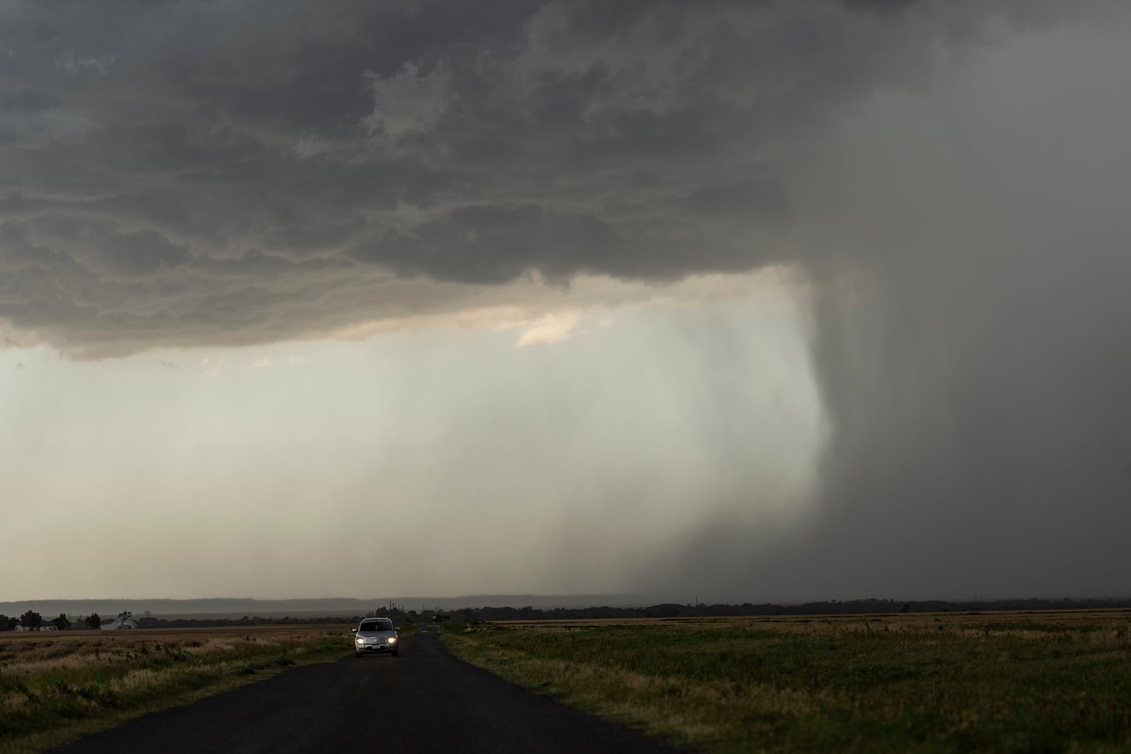 A car moves away from an approaching storm with a rain shaft during a Project ICECHIP operation on Tuesday, June 3, 2025, near Tipton, Okla. (AP Photo/Carolyn Kaster)