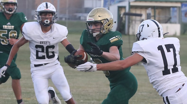 Catholic Central's Ashton Young carries the ball between Greenon's Zach Stevens, left, and Tallyn Peterson. BILL LACKEY/STAFF