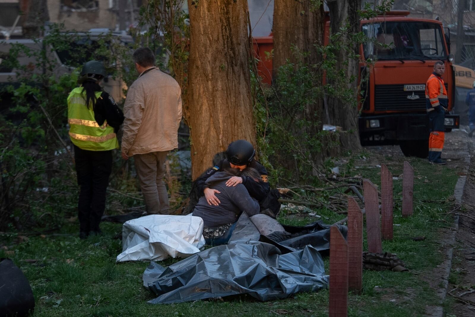 A rescue psychotherapist hugs a woman who lost a loved one, in front of the bodies of victims after a Russian strike in a residential neighborhood in Kyiv, Ukraine, Thursday, April 24, 2025. (AP Photo/Alex Babenko)