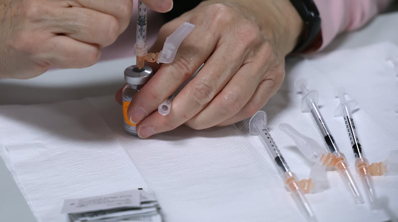 Coronavirus cases in Clark and Champaign County schools nearly double in a week. Here, Peggy Smith gets a Moderna vaccine ready for someone at the Clark County Combined Health District's Vaccination Center earlier this month. BILL LACKEY/STAFF