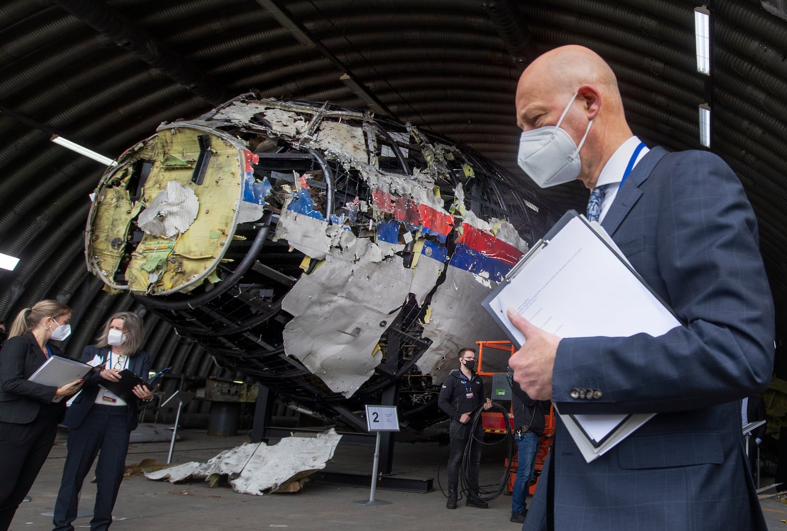FILE - Presiding judge Hendrik Steenhuis, right, other trial judges and lawyers view the reconstructed wreckage of Malaysia Airlines Flight MH17, at the Gilze-Rijen military airbase, southern Netherlands, on May 26, 2021. (AP Photo/Peter Dejong, Pool, File)