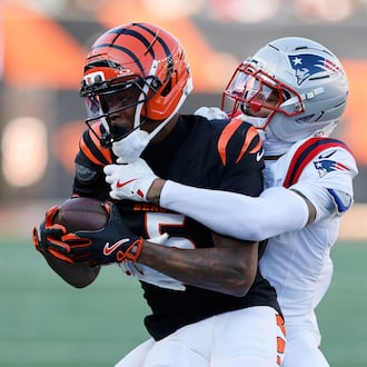 Cincinnati Bengals wide receiver Tee Higgins (5) is tackled by New England Patriots cornerback Carlton Davis III after catching a pass during the second half of an NFL football game, Sunday, Nov. 23, 2025, in Cincinnati. (AP Photo/Jay LaPrete)