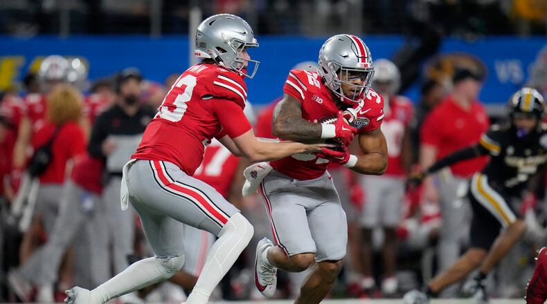 Ohio State quarterback Devin Brown, left, hands off to running back TreVeyon Henderson during the first half of the team's Cotton Bowl NCAA college football game against Missouri on Friday, Dec. 29, 2023, in Arlington, Texas. (AP Photo/Julio Cortez)