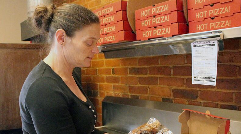 Enon Pizza & Company owner Tracy Wiggins gets ready to box up a hot pizza. JEFF GUERINI/STAFF