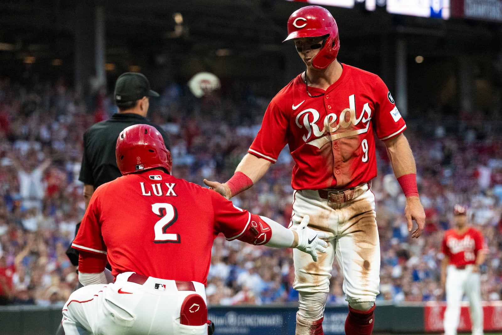 Cincinnati Reds' Matt McLain (9) and Gavin Lux (2) celebrate after McLain scored in the third inning of a baseball game against the Chicago Cubs, Saturday, Sept. 20, 2025, in Cincinnati. (AP Photo/Michael Swensen)