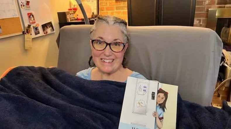 Kathy Reno poses with a book she wrote following her ALS diagnosis. CONTRIBUTED