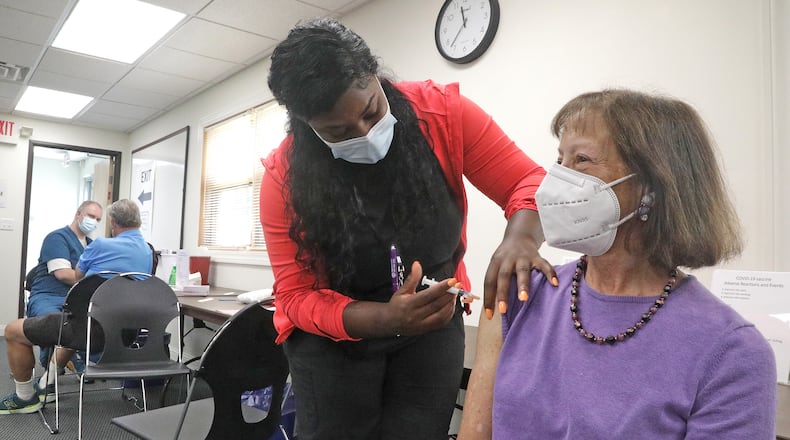 Claudia Fett gets her COVID booster shot in the fall from Ocie Orr, a nurse in the Vaccine Clinic at the Clark County Combined Health District. BILL LACKEY/STAFF