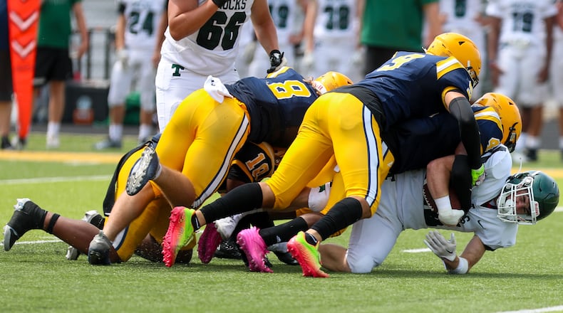 Cutline 2: A group of several Springfield High School defensive players bring down a Louisville Trinity player during their scrimmage game on Aug. 5 in Springfield. CONTRIBUTED PHOTO BY MICHAEL COOPER