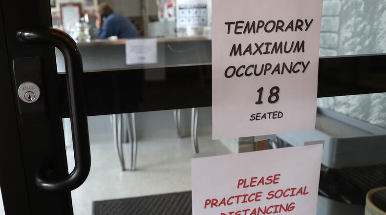 A sign on the entrance to The Fountain On Main says the maximum occupancy has been reduced to 18 customers in order to follow social distancing guidelines. BILL LACKEY/STAFF