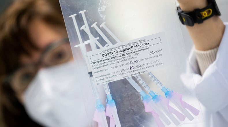 A healthcare worker shows a bag of syringes containing the Moderna new coronavirus vaccine immediately before a vaccination at the University Hospital in Essen, Germany, Monday, Jan. 18, 2021. The Corona vaccination campaign in the German state of North Rhine-Westphalia has been extended to hospital staff. (Rolf Vennenbernd/dpa via AP)
