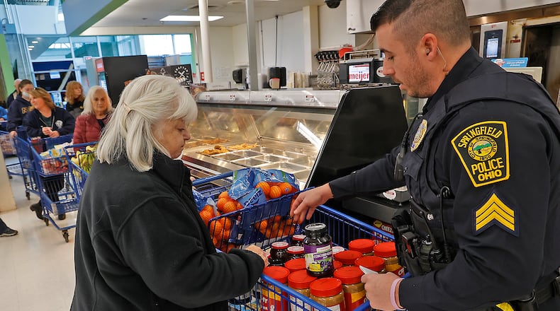 Springfield Police Sgt. Thomas Potter and volunteer Vicki Matthies check out at a cash register in Meijer last year during Operation Thanksgiving, a partnership between the Springfield Police Division, the Clark State College Criminal Justice Club and Meijer, which provides a Thanksgiving meal and food for the holidays for needy families in Springfield. BILL LACKEY/STAFF