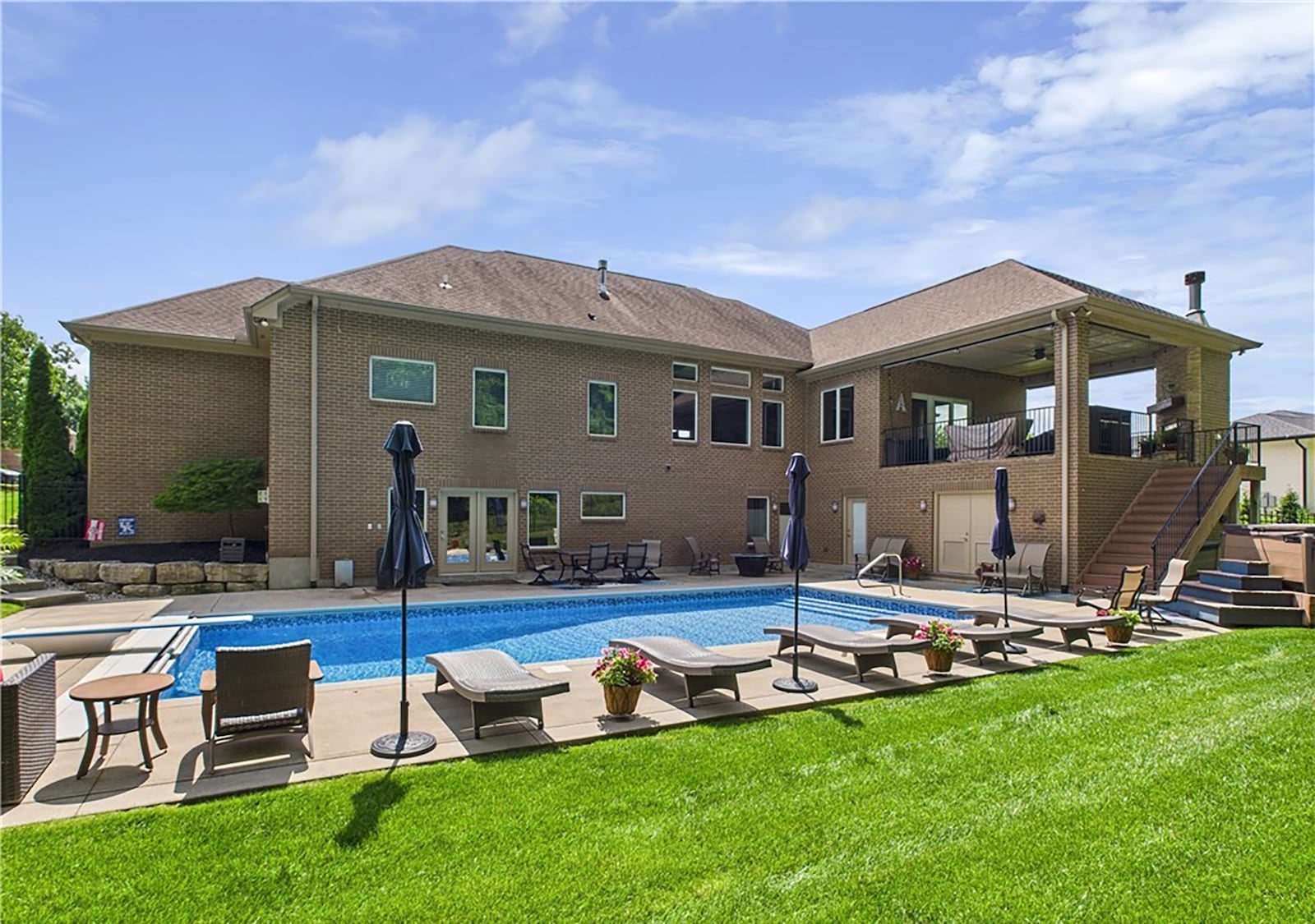 The back of the home is surrounded by a metal fence and has two levels of outdoor space.