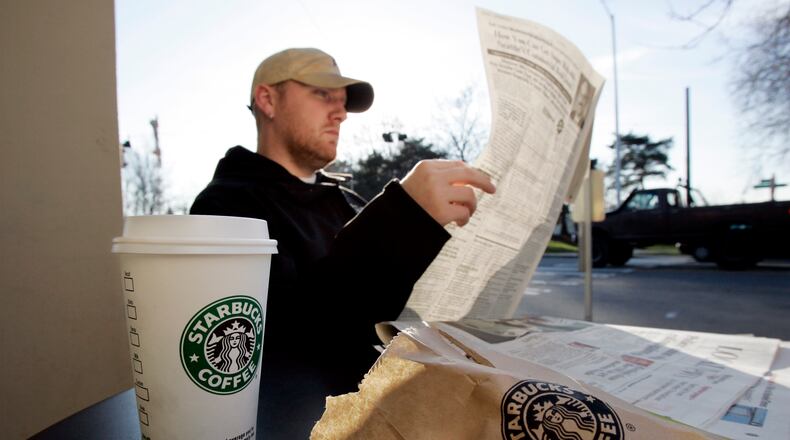 ** FILE ** J.J. Geise reads a paper as he treats himself to coffee and a baked good at a Starbucks coffee shop in Seattle in this Jan. 25, 2008 file photo. Starbucks Corp. is teaming up with AT&T Inc. and will start offering a mix of free and paid wireless Internet service in many of its U.S. coffee shops, beginning this spring. (AP Photo/Elaine Thompson, file)