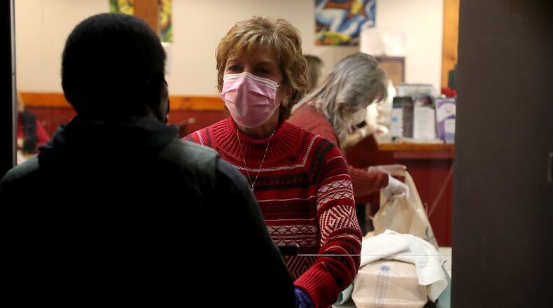 Volunteers give out Thanksgiving meals through a doorway at the Springfield Soup Kitchen Wednesday. BILL LACKEY/STAFF