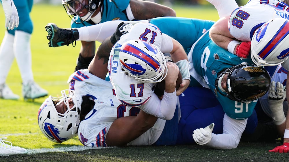 Buffalo Bills quarterback Josh Allen (17) pushes in for a first down as Jacksonville Jaguars defensive tackle Arik Armstead (91) tries to stop him during the second half of an NFL wild-card playoff football game Sunday, Jan. 11, 2026, in Jacksonville, Fla. (AP Photo/Chris O'Meara)