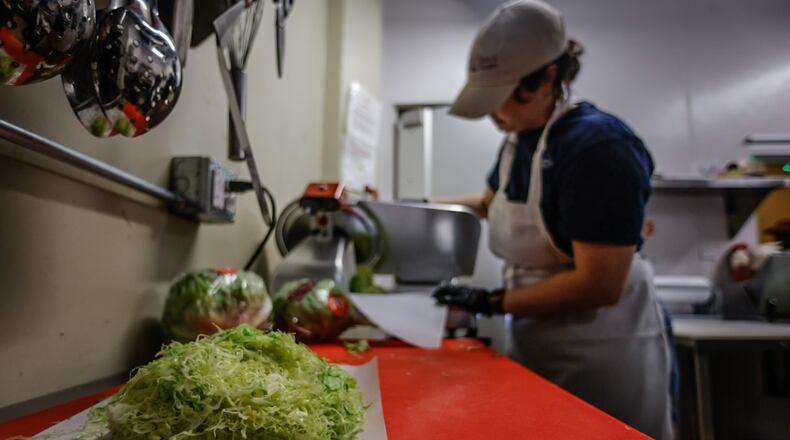 Tony & Pete's Groceries & Coldcuts cook Casey Harner shreds heads of lettuce at the store Thursday, Dec. 22, 20022. Lettuce prices have been increasing for months, causing restaurants to swallow the cost or remove the leafy green as an option. The store is at 129 East Third St. in Dayton. JIM NOELKER/STAFF