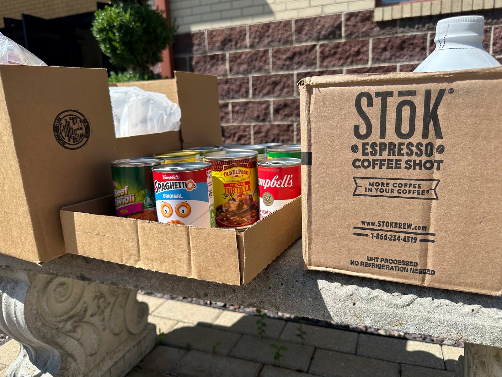 Cans and boxes of food sit on a bench outside the Samaritan Center food pantry in Jefferson City, Mo., on Tuesday, July 1, 2025. (AP Photo/David A. Lieb)