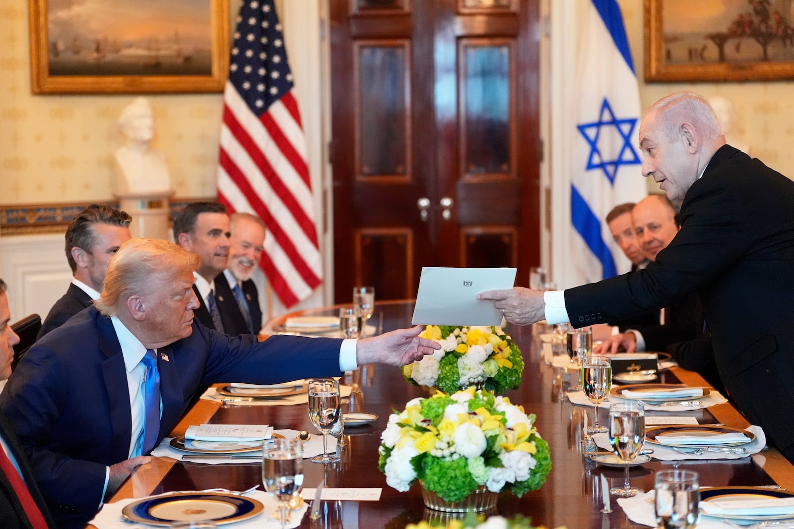Israel's Prime Minister Benjamin Netanyahu, right, hands President Donald Trump a folder during a meeting in the Blue Room of the White House, Monday, July 7, 2025, in Washington. (AP Photo/Alex Brandon)